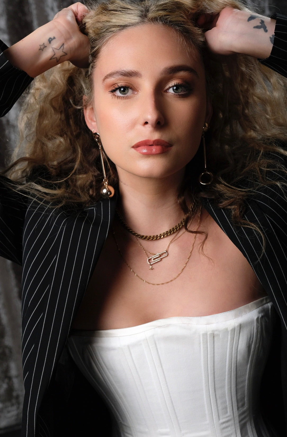 Close-up of a light-skinned woman wearing a white Freja corset with a dark pin stripe blazer.