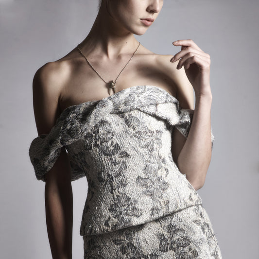 Close-up of a light-skinned woman wearing an Emerald Faerie vintage fabric corset with a matching skirt.