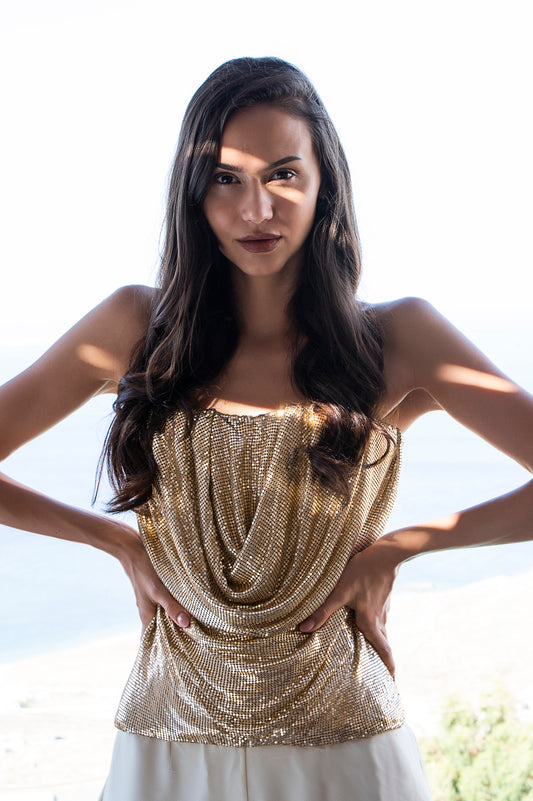 Brown haired and medium-skinned woman wearing a gold chainmail Deborah Brand Dua corset.