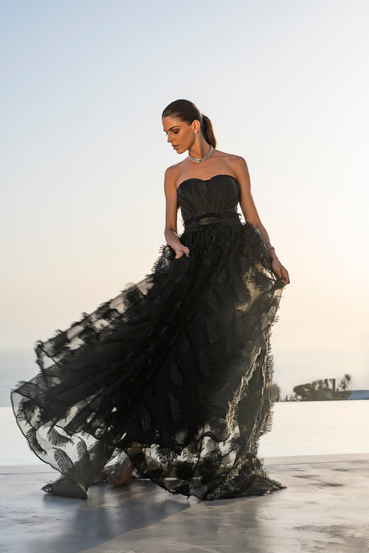 Light-skinned woman wearing a black Deborah Brand Katherine corset with a flowing black skirt.