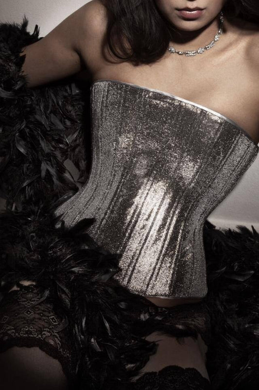 Close-up shot of a light-skinned woman wearing the Jourdan bespoke corset with stockings and a boa.
